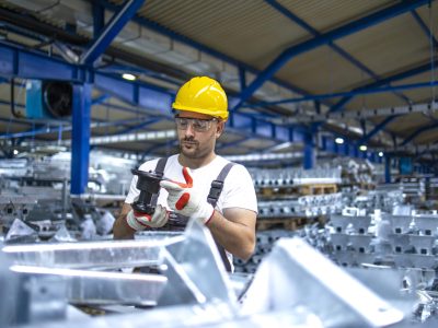 Factory worker working in industrial production hall.